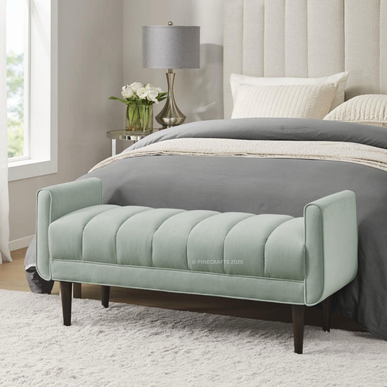Light green upholstered bench in front of a bed with gray bedding.